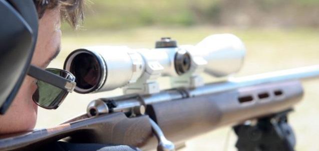 Man aiming a rifle equipped with a scope, showcasing improve shooting accuracy tips