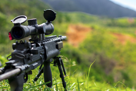 Rifle with scope set up in a green outdoor terrain for improve shooting accuracy tips