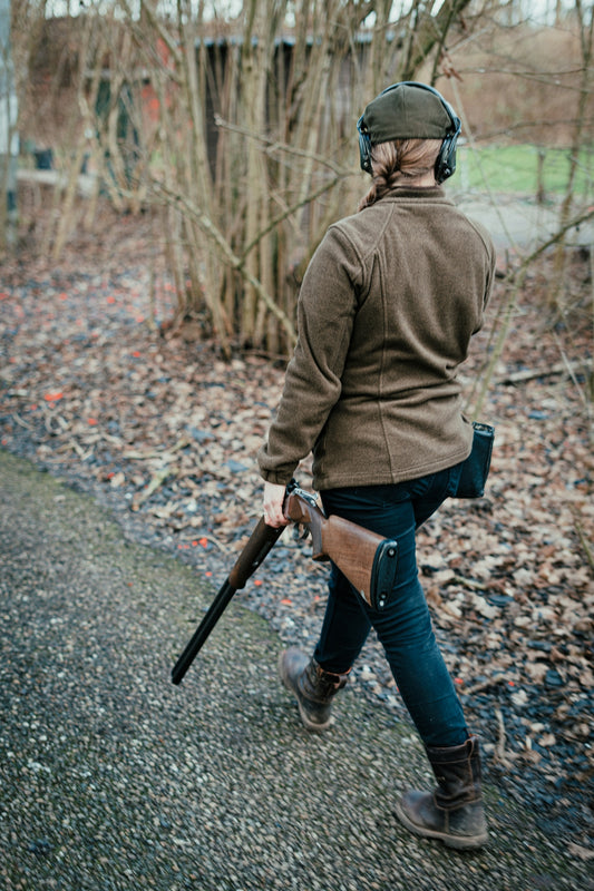 a woman walking down a road holding a rifle