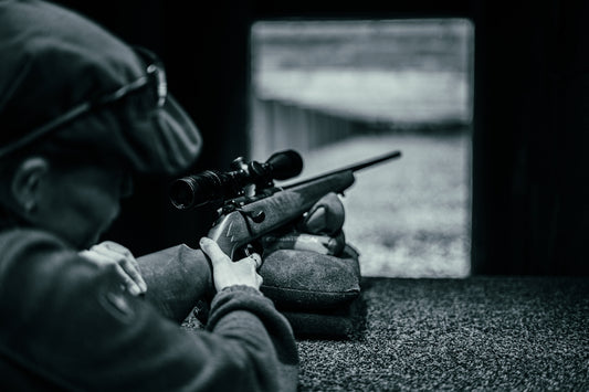 a person sitting on the ground with a rifle
