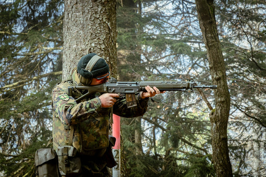 a man in camouflage holding a rifle in the woods