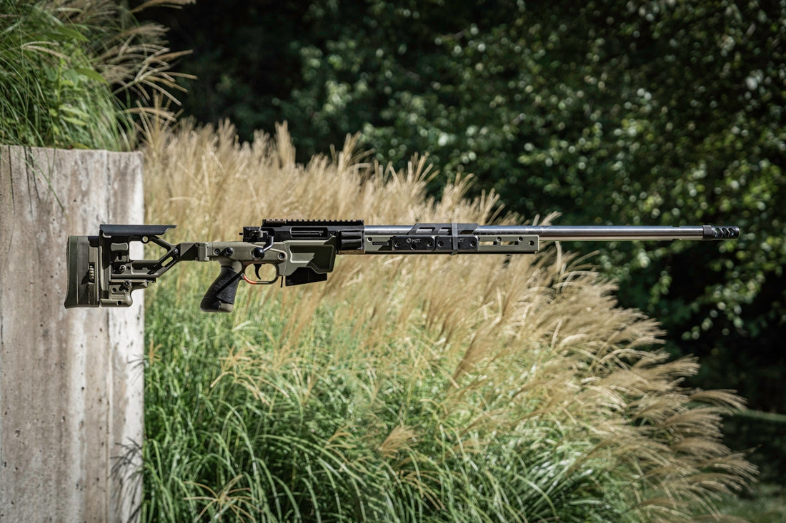 A rifle mounted to a wooden post in front of tall grass