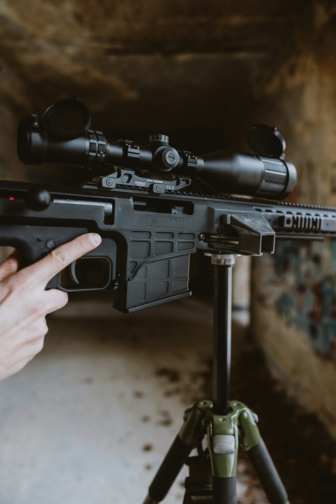 A person aims a rifle mounted on a tripod.