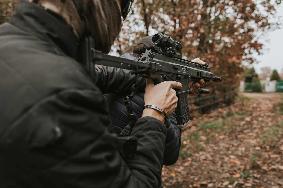 Person aiming a rifle in a wooded area