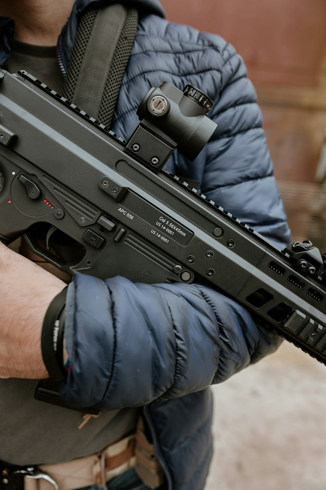 Man holding a modern assault rifle with scope.