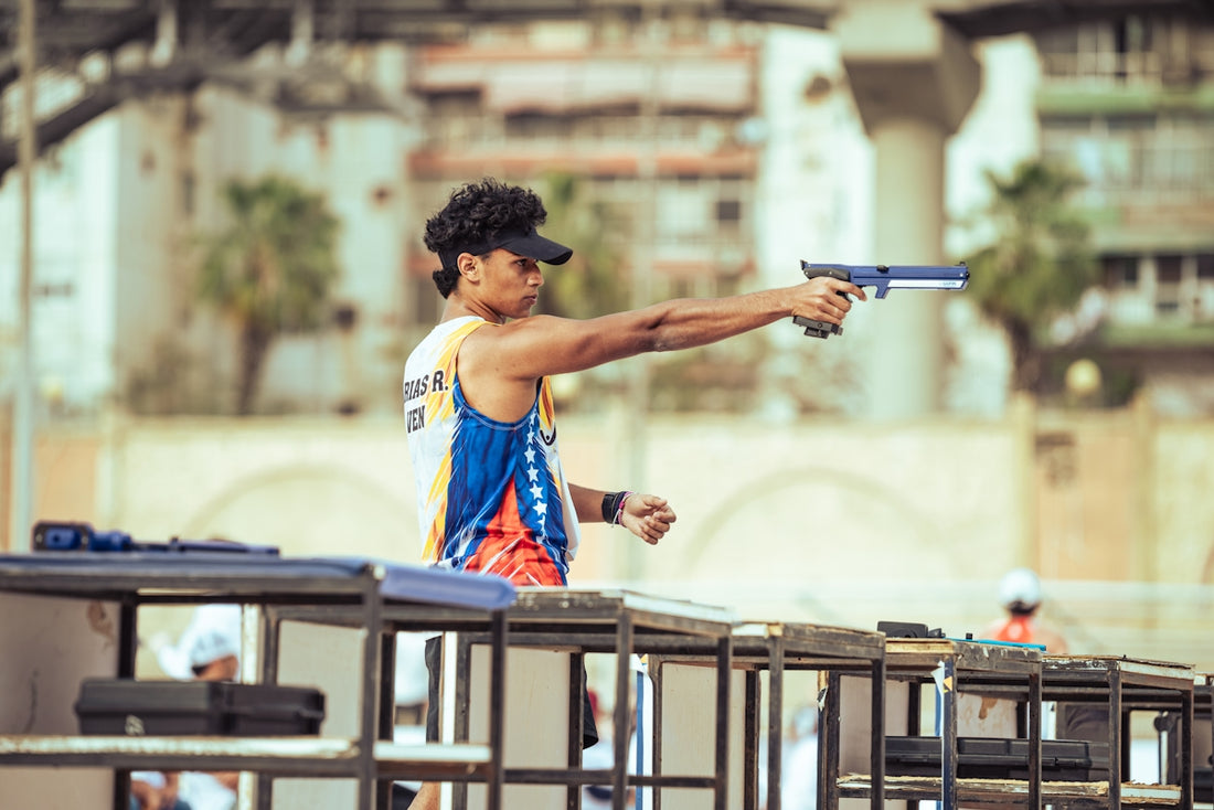 Athlete aiming a pistol during an outdoor shooting competition.